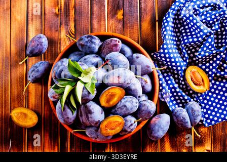 Fresh plums on plate over wooden background Stock Photo