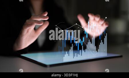 A business professional engages with a digital tablet displaying financial graphs, showcasing the power of modern technology in data analysis and Stock Photo
