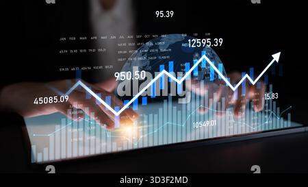 Hands interact with a digital tablet displaying financial graphs and a glowing globe, representing data analysis and growth in the finance sector Stock Photo