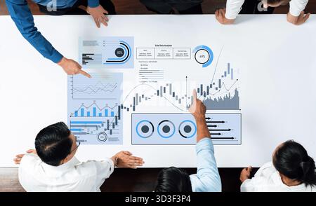 A team of professionals collaborates at a table discussing business data analysis. Charts, graphs, and visual aids highlight key insights and Stock Photo