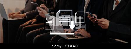 A diverse group of business professionals actively engaged in downloading files on devices during a meeting. The focus on technology showcases modern Stock Photo
