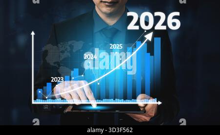 A businessman interacts with a digital tablet displaying a financial growth graph. The chart shows annual projections, highlighting growth potential Stock Photo