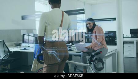 Two colleagues discussing work beside white bicycle in open-plan office, with printed documents Stock Photo