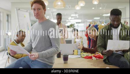 Red-haired male designer reviewing sketches at open-plan design studio table, copy space Stock Photo