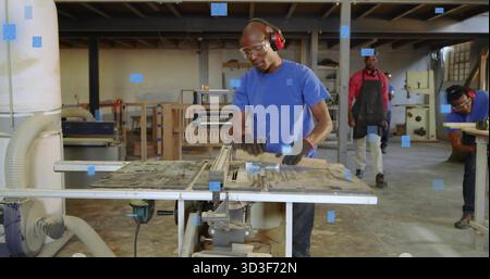 Operating carpenter feeding wooden board through table saw in workshop, with sawdust and gloves Stock Photo