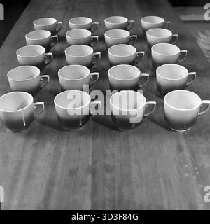 An archival photo from the 1990s shows consumer goods (TNP) from the AIZ (Armature-Insulator Plant) in Sloviansk, Ukraine. This is a display of finished products. Twenty identical ceramic cups are arranged in four neat rows of five on a wooden table. The cups feature a distinctive faceted design and a two-tone gradient glaze. This image shows the consumer goods production line of a major industrial factory. This captures industrial history in the peaceful Donbas before the war. Stock Photo