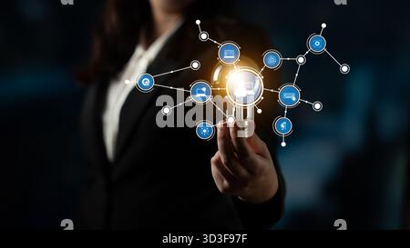A businesswoman showcases a glowing light bulb surrounded by digital icons, symbolizing innovation and technology in a modern and professional setting Stock Photo