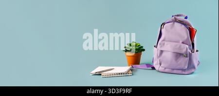 A backpack filled with stationery with flowers on an isolated blue background with a place for text, the September 1 concept for schoolchildren and st Stock Photo