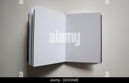 An open sketchbook showing two blank white pages on a neutral light gray background. Ideal for mockup, design presentation, illustration of writing, l Stock Photo
