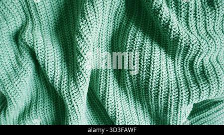 Close up of a knitted blanket or sweater texture in a vibrant mint, emerald, or turquoise color. Cozy, warm background for autumn, winter, or holiday Stock Photo