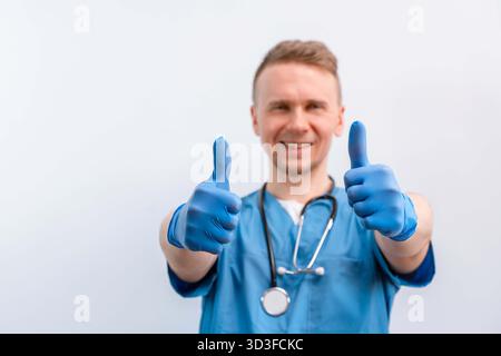 Young man caucasian doctor in blue uniform doing thumb up over isolated pink background Stock Photo