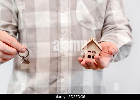 The man bought the property and holds the keys in one hand, and the model of the house in the other hand. Stock Photo