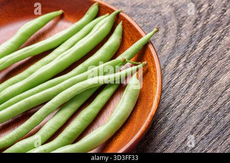 Closeup view of fresh green beans on wooden plate Stock Photo