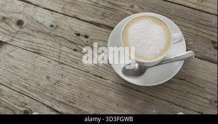Displaying white ceramic coffee cup resting on tabletop, with metal teaspoon on saucer, copy space Stock Photo