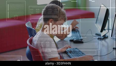 Working elementary students typing code on desktop monitors in coding lab, with digital overlays Stock Photo