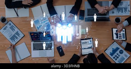 A modern business meeting scenario featuring professionals engaged in teamwork and technology, with digital graphics illustrating data analysis and Stock Photo