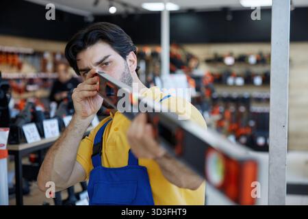 A man worker taking measurements using a bubble level tool inside a store Stock Photo