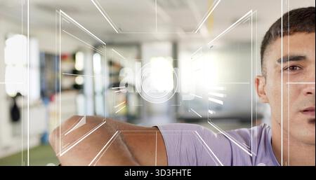Raising man showing right-side face, arm crossing at gym in purple tee, HUD overlay, copy space Stock Photo