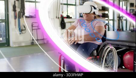 Using VR woman wearing pink tee and pants doing exercises at rehab gym, with red wheelchair Stock Photo