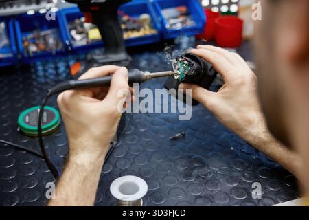 A man using a soldering iron on electronic equipment Stock Photo