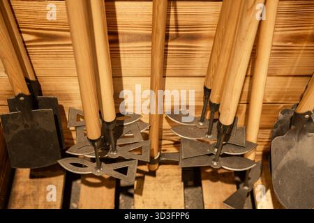 Set of different garden tools with wooden handles arranged on wooden wall background in workshop or store. Stock Photo