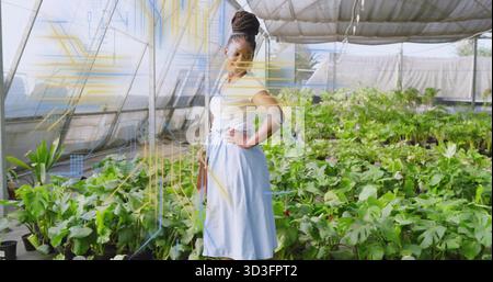 Standing woman wearing white top and blue skirt, posing in nursery with pots and crossbody bag Stock Photo
