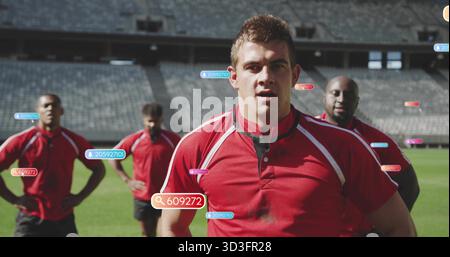 Standing front-center athlete wearing red jersey and black shorts on grass pitch, with digital tags Stock Photo