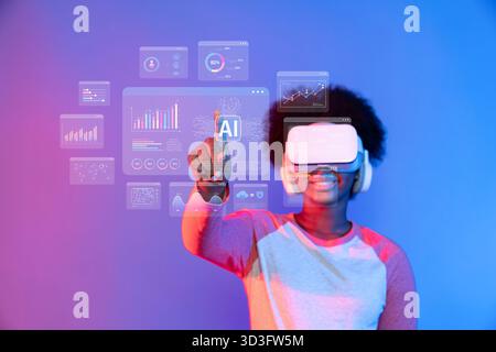 A young user wearing a virtual reality headset interacts with AI-driven data analytics and visualizations in a futuristic digital workspace Stock Photo