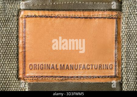 Patch label sais Original Manufacturing stitched on khaki green fabric background closeup Stock Photo