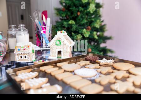 A festive scene in Quito, Ecuador, featuring beautifully decorated gingerbread houses and an assortment of Christmas cookies on a tray, set beside a d Stock Photo