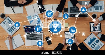 A dynamic meeting scene showcasing professionals collaborating on business strategies. Tools like laptops and tablets display charts and graphs for Stock Photo