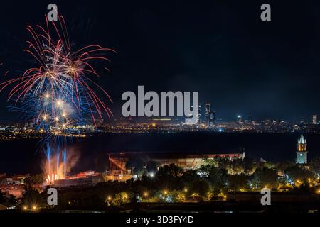 Vibrant fireworks light up the night sky in Colmenar Viejo, Madrid, creating a spectacular display over the cityscape. The fireworks add a festive glo Stock Photo
