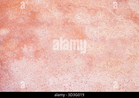 Close-up of a textured concrete surface in soft orange tones. The abstract pattern displays subtle variations, creating a natural, tactile background Stock Photo
