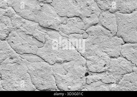 A close-up image of a rough, cracked concrete surface exhibiting a textured pattern in light gray. The uneven cracks and granular details create a nat Stock Photo