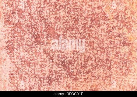 A close-up image showcasing the naturally textured surface of red stone. Its rough patterns and intricate details create a captivating abstract backgr Stock Photo