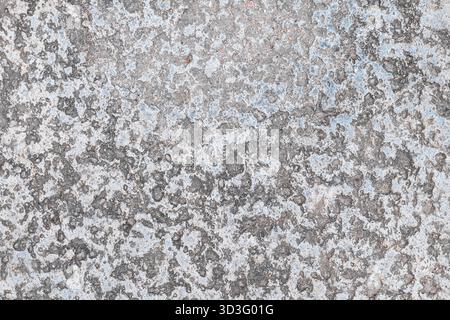 Close-up of a weathered concrete surface displaying intricate gray patterns with hints of blue and white. The rough texture and organic design create Stock Photo