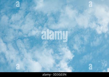 A beautiful image of the blue sky with white, scattered clouds forming a textured pattern. The serene and airy composition provides a sense of calm an Stock Photo