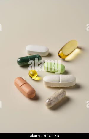 Top view of assorted pills and supplements, including capsules and tablets in various colors and shapes, arranged on a soft beige background, highligh Stock Photo