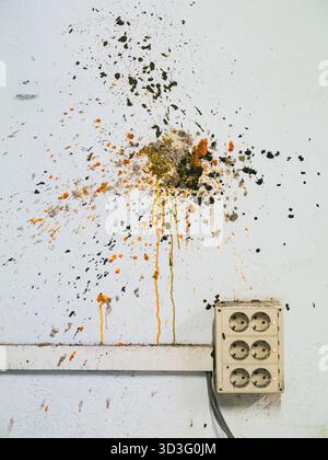 An old electrical outlet on a worn wall, marked with colorful paint splatters. The image captures a blend of neglect and artistic expression in an aba Stock Photo
