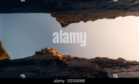 A striking perspective of the majestic cliffs at Playa de Las Catedrales in Galicia, showcasing the rugged textures and dramatic angles under a soft, Stock Photo