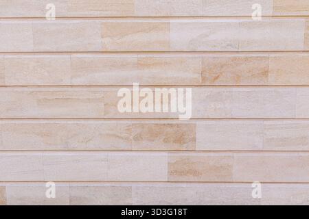 Beige tiled wall featuring a horizontal pattern. The texture and color provide a natural and rustic feel, ideal for backgrounds and architectural them Stock Photo