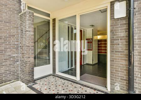 A stylish modern entrance featuring a glass door, tiled flooring, and an inviting ambiance, showcasing contemporary architectural design Stock Photo