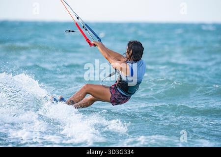 A woman enjoys kitesurfing in the vibrant blue waters of Mayapo, La Guajira, Colombia. The wind and waves create the perfect backdrop for an exhilarat Stock Photo