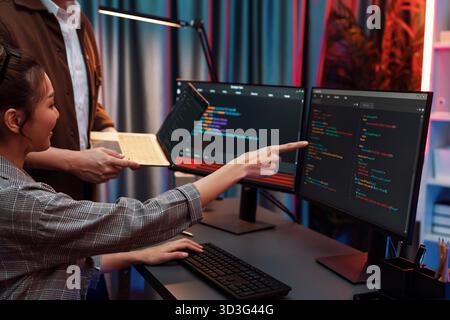 Serious of IT developers discussing intelligent website development coder system running data online two screens with laptop showing information Stock Photo