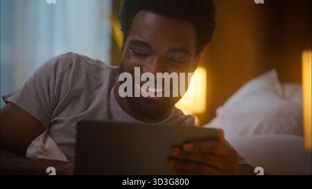 Happy cheerful smiling African American ethnic man male guy client user holding digital tablet using device watching online video browsing internet Stock Photo
