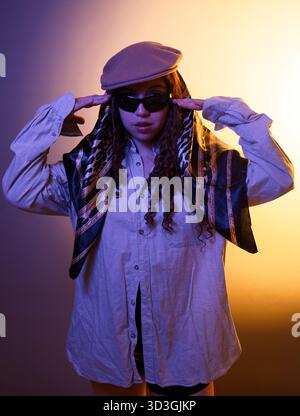 Woman posing confidently, embracing her unique style in a studio with colored light Stock Photo