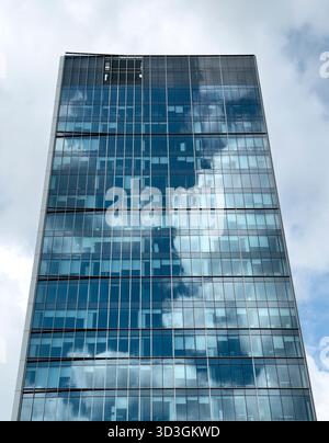 Futuristic skyscraper rising. Modern corporate tower with glass windows and reflective facade, symbol of architecture, innovation, business developmen Stock Photo