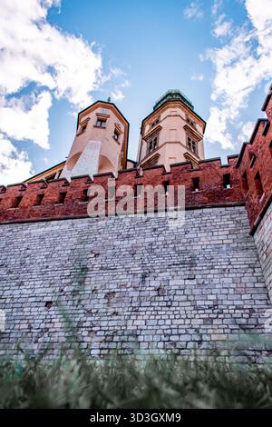 A building surrounded by a wall made of red and white bricks. A view from below of the towers. Stock Photo