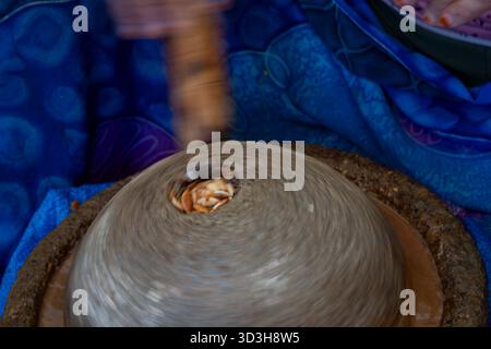 Argan oil extraction by traditional stone handmill. A Berber woman extracts argan oil, Essaouira, Morocco, North Africa. Closeup, movement. Stock Photo