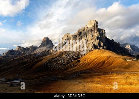 Spectacular snow-capped mountains surrounding iconic Passo Giau pass in the Dolomites, Italy, with vibrant golden autumn larches. Stock Photo
